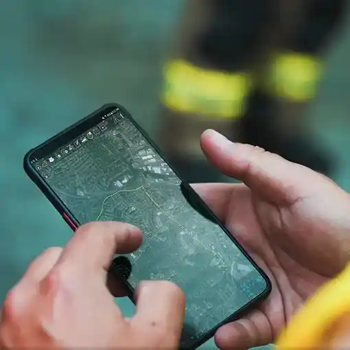 a man holding a phone running the ATAK app